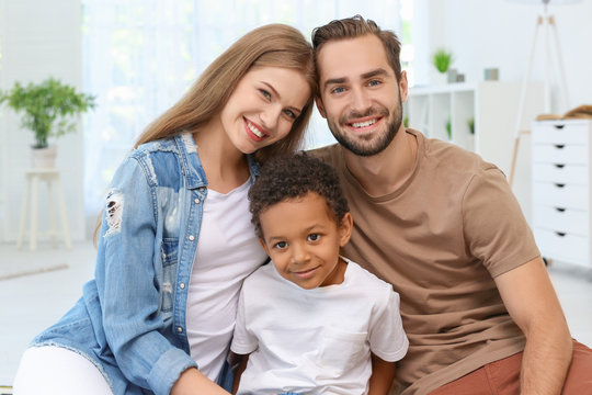 Happy couple with adopted African-American boy at home