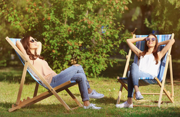 Beautiful young women sunbathing in park - obrazy, fototapety, plakaty