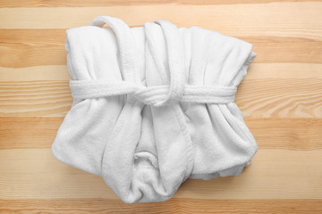 Folded white bathrobe on wooden background