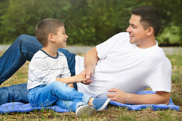 Happy father and son resting in park