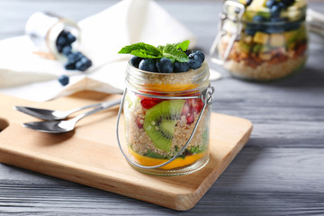Fruit salad with quinoa served in glass jars on kitchen table