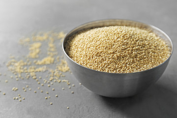 Raw quinoa in metal bowl on grey background
