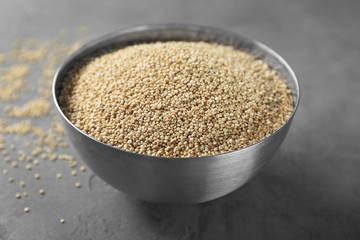 Raw quinoa in metal bowl on grey background