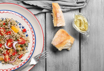 Salad with quinoa, tomatoes and onion served on grey wooden background