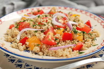 Salad with quinoa, tomatoes and onion on plate, closeup