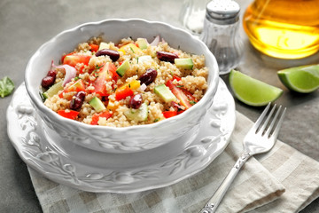 Salad with quinoa, tomatoes and beans served in bowl on grey background