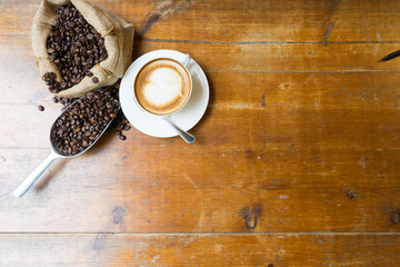 cup of coffee, coffee beans, bag on a wood table on a wooden background