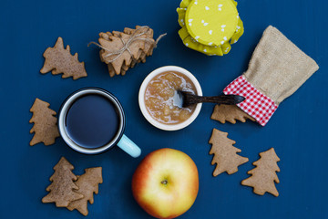 A cup of tea with jam, christmas tree cookies and apples on the dark blue background