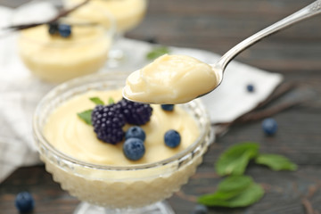 Teaspoon and dessert bowl with vanilla pudding on blurred background
