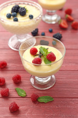 Composition with vanilla pudding, fresh mint and berries on wooden background