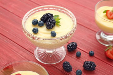 Composition with vanilla pudding and berries on wooden background