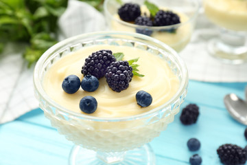 Composition with vanilla pudding, blueberries and blackberries on wooden table