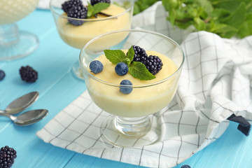 Composition with vanilla pudding, blueberries and blackberries on wooden table