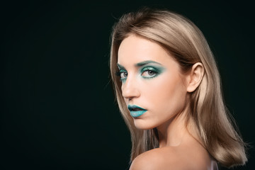 Naklejka premium Young woman with bright green makeup on black background
