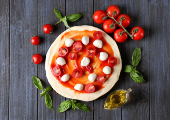 Composition with green fresh basil and ingredients for pizza on wooden background