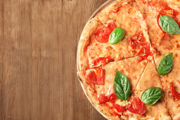 Delicious pizza with tomatoes and fresh basil on wooden background