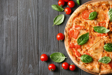 Composition with pizza, cherry tomatoes and fresh basil on wooden background