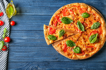 Composition with pizza, oil, cherry tomatoes and fresh basil on wooden background