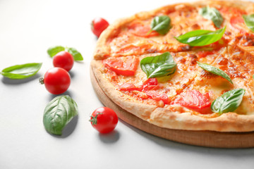 Delicious pizza, cherry tomatoes and fresh basil on light background