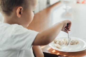 A hungry child is eating dumplings in the kitchen
