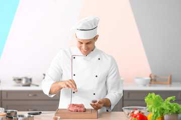 Young male chef cooking meat in kitchen