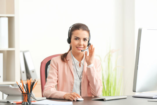Young female receptionist wearing headphones in office - Powered by Adobe