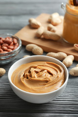 Ceramic bowl with creamy peanut butter on kitchen table