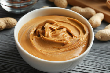 Ceramic bowl with creamy peanut butter on kitchen table