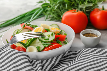 Healthy salad with cucumbers and eggs in bowl on table