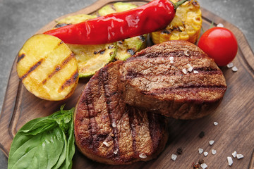 Composition with tasty grilled steaks on table, closeup