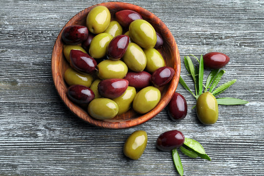 Bowl with tasty olives on wooden background