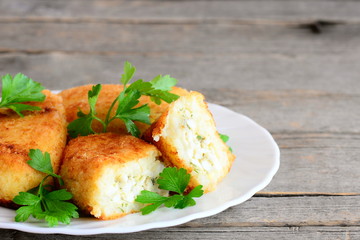 Stuffed vegetable cutlets on a serving plate and a vintage wooden background. Cutlets made from cauliflower and potatoes and stuffed with hard boiled sliced eggs. Closeup