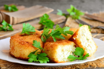 Stuffed vegetable cutlets on a serving plate. Cutlets cooked from cauliflower and potatoes and stuffed with hard boiled sliced eggs. Rustic style. Closeup