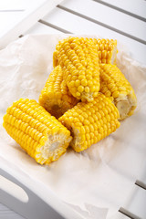 Boiled sweet corn cob with butter and salt on table.
