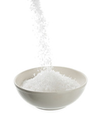 Pouring sea salt in porcelain bowl isolated on white background.   