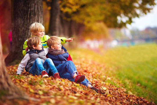 happy kids, friend having fun among fallen leaves in autumn park