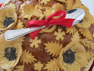 Two spoons wound with a red ribbon lie on the traditional bread. Wedding tradition of the Slavic peoples. Crown decoration for wedding celebration. Birds, rings and flowers on dough cows.