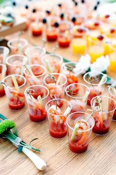Beautiful lines of different alcohol and non-alcohol cocktails. Snack cocktails with tomato juice and shrimps. Vertical photo. Catering table for party.