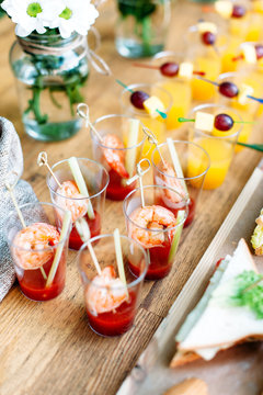 Beautiful row line of different alcohol and non-alcohol cocktails. Snack cocktails with tomato juice and shrimps. Vertical photo. Catering table for party.