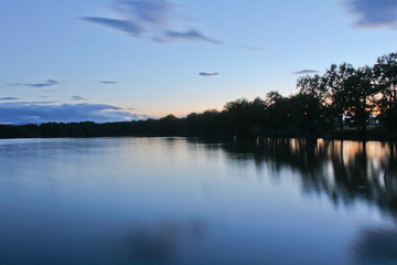 Obraz premium Sunset on pond with trees silhouette and orange sky, long exposure, Czech landscape