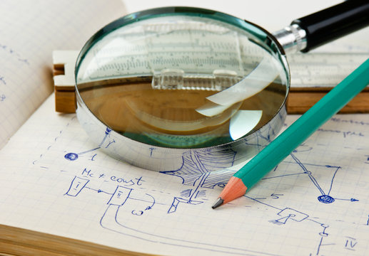 magnifying glass and a slide rule on the old page with the calculations in mechanics