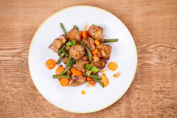 Beef liver with vegetables: carrot, onion and green beans on white plate. Top, overhead, above view, horizontal