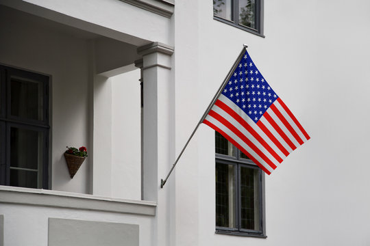 USA flag. American flag displaying on a pole in front of the house. National flag of United States of America waving on a home hanging from a pole on a front door of a building.