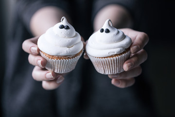 Female hands holding two Halloween cupcakes