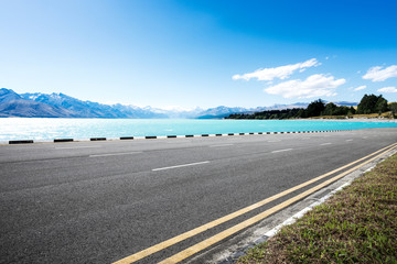 empty asphalt road with beautiful lake in blue sky