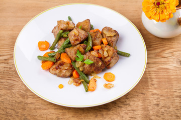 Beef liver with vegetables: carrot, onion and green beans on white plate, horizontal