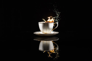 Coffee splashes in white cup on black background