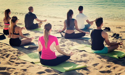 People in lotus positions looking at sea