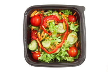 Fresh salad in a plastic container isolated on white background. Top view