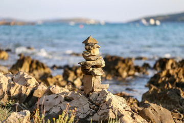 Fototapeta na wymiar Column laid out of stones near the sea